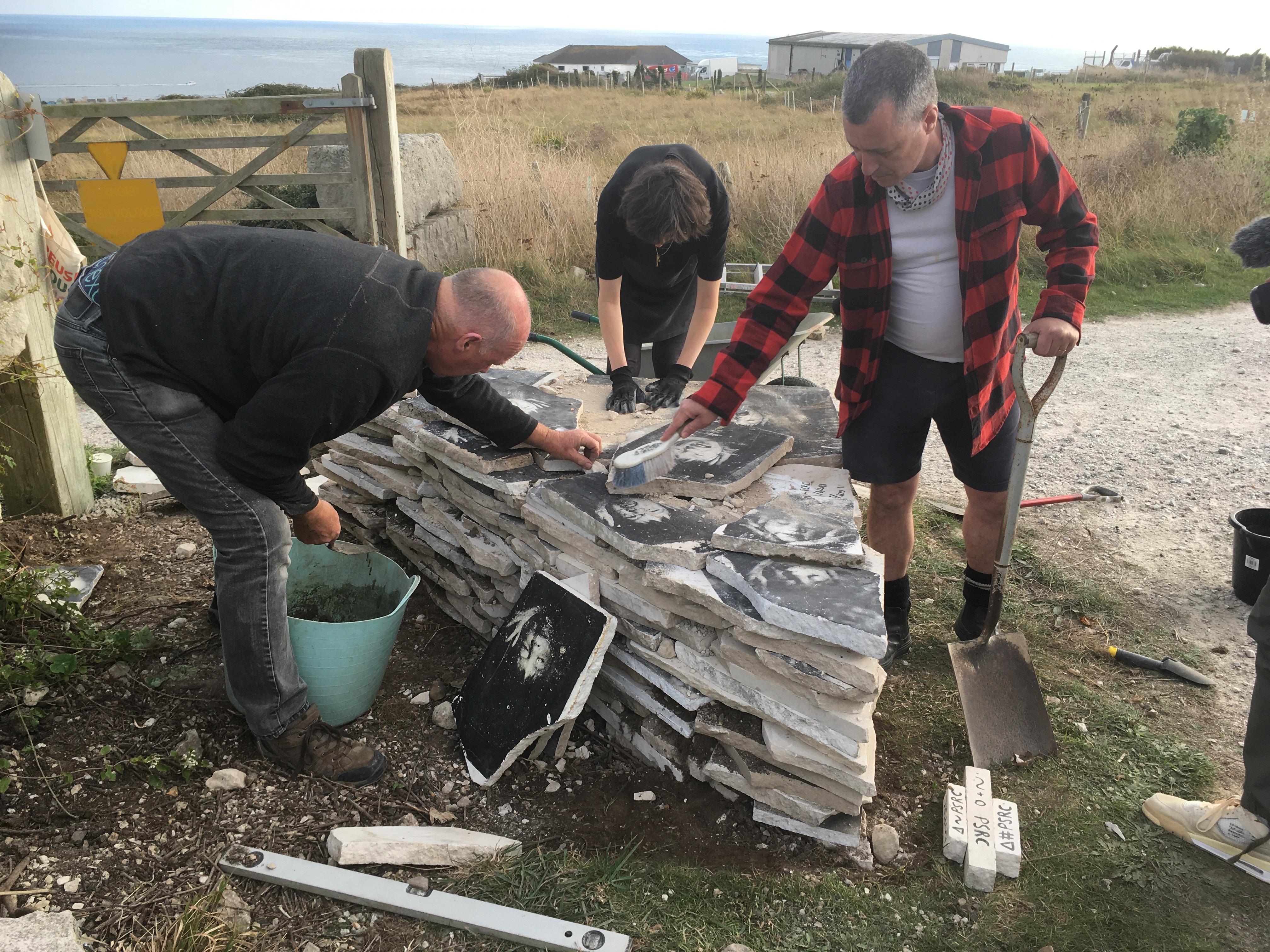 3 people working with stone slabs making a stacked shape