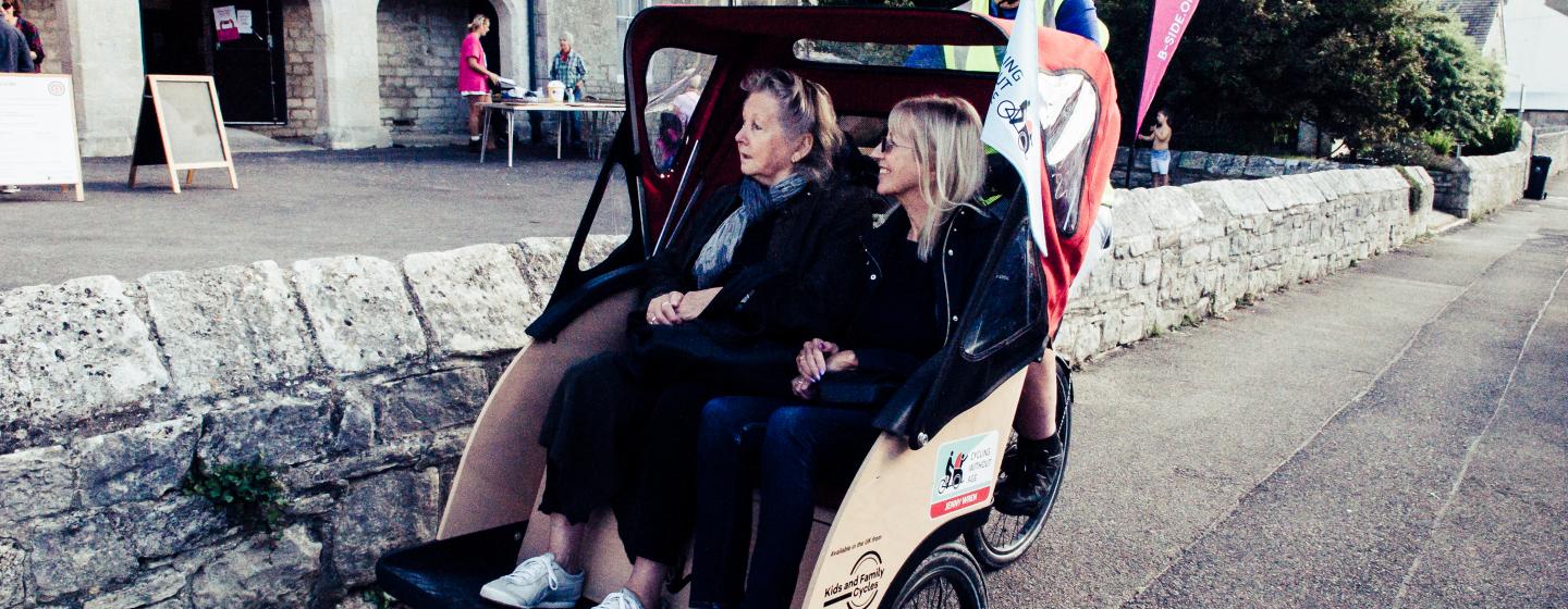 Two people sitting on a Trishaw, being cycled around
