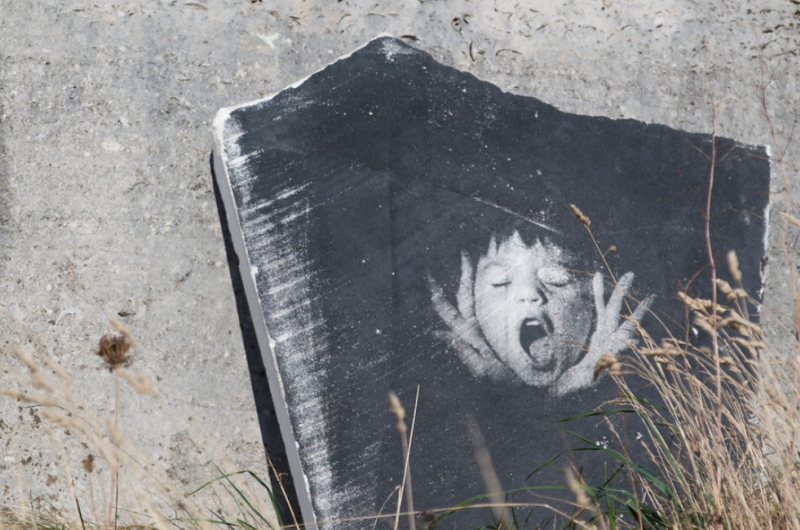 Image of a boys face screaming imprinted on a stone surface
