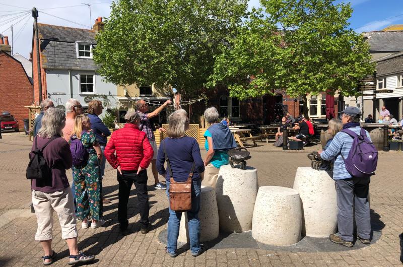 A group of people stand by stone sculptures talkinh