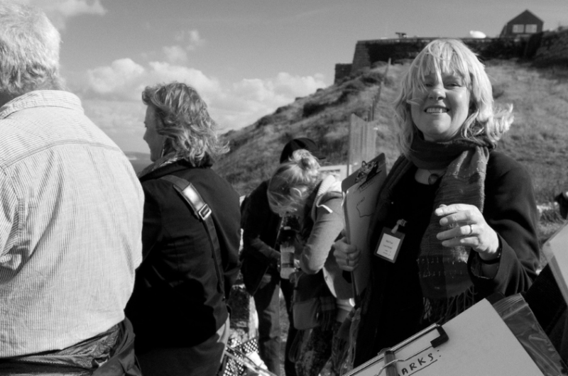 A group of people with clipboards looking out over Portland, a woman with blonde hair smiles into the camera