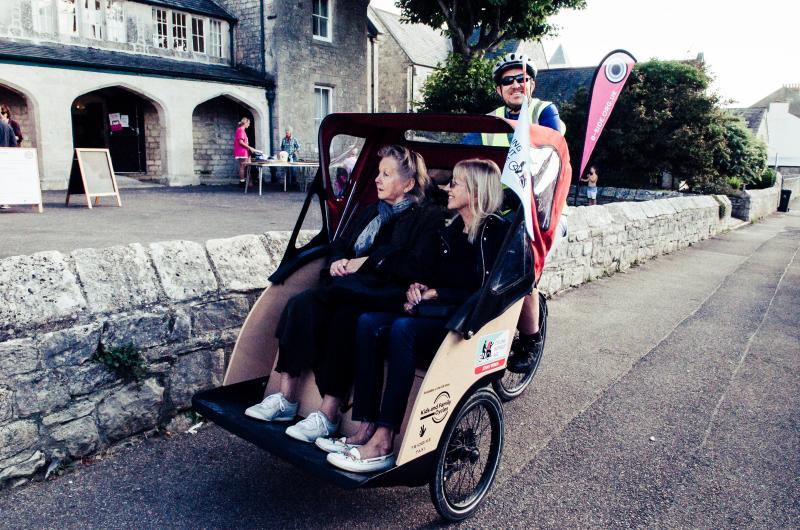 Two people sitting on a Trishaw, being cycled around