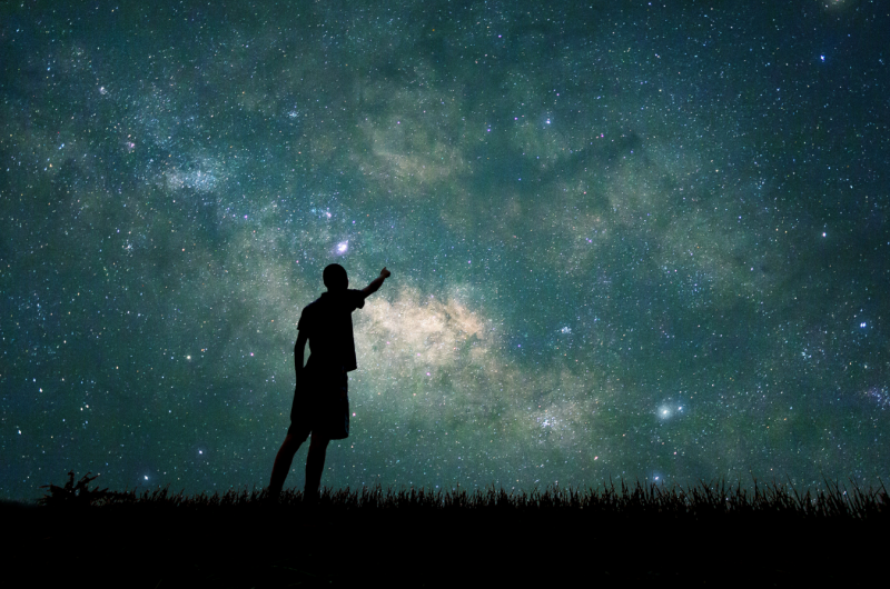 A photograph of the night sky with a person in silhoette