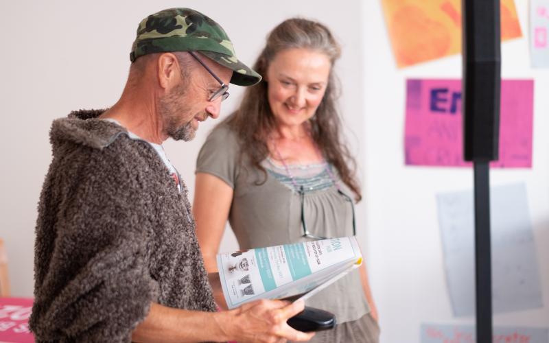 A man and woman standing and looking at a brochure