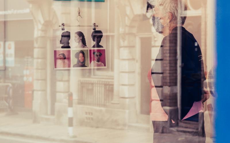 A woman looking at some artwork on the walls, picture taken through a window