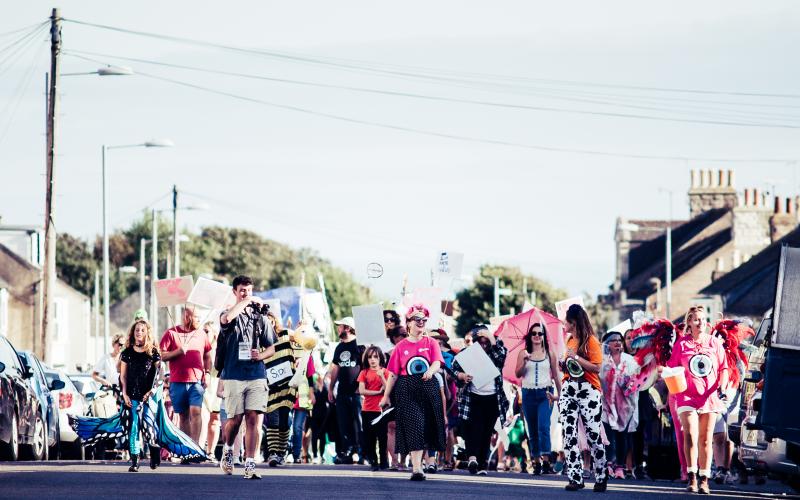 A group of people dressed up, with signs, walking down the road