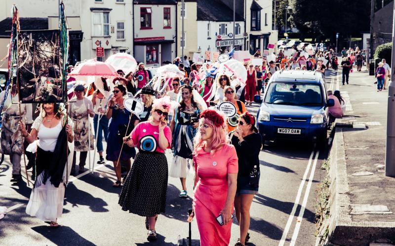 A group of people dressed up, with signs, walking down the road