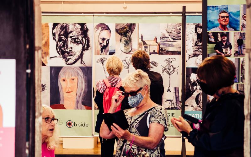 Several people looking at an exhibition of large posters