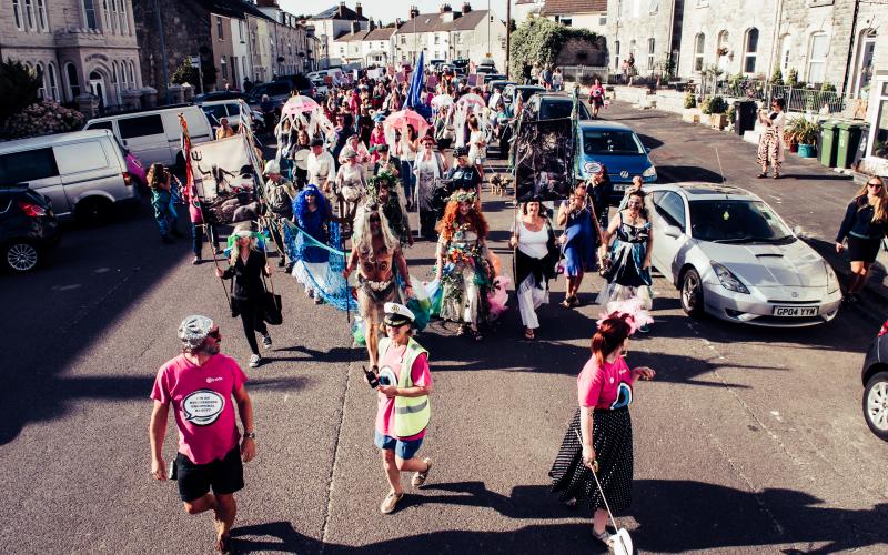 A group of people dressed up, with signs, walking down the road
