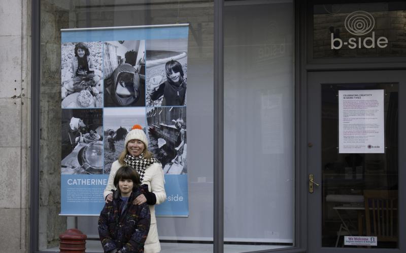 A woman and a child stand in front of a poster