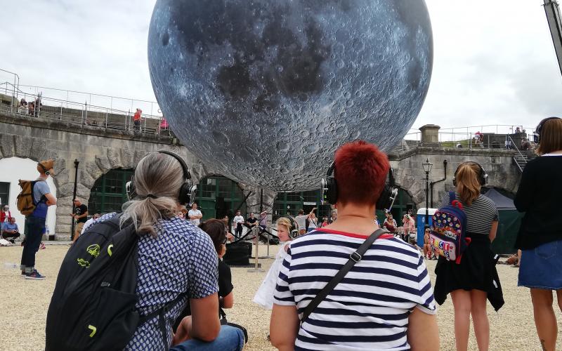 Dorset Moon at Nothe Fort Photo Sandy Kirkby Two people looking at Museum of the Moon by Luke Jerram