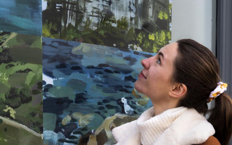 A close up of a young woman looks at her artwork
